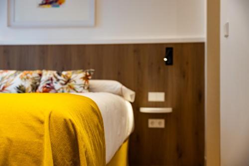a bedroom with a bed with a yellow blanket at Hostal Paris in Valladolid