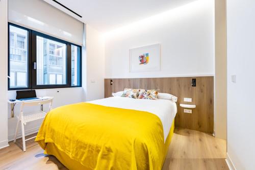 a bedroom with a large bed with a yellow blanket at Hostal Paris in Valladolid