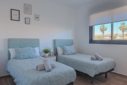 a bedroom with two beds and a window with palm trees at Luxury 2 Bedroom Apartment BY COELI HOLIDAYS in Los Alcázares