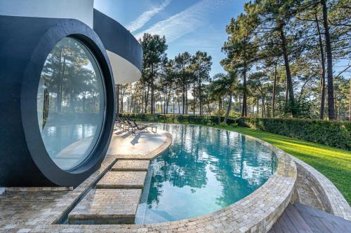 uma piscina circular num parque com um espelho redondo em Moradia T5 com golfe e piscina na Caparica em Aroeira