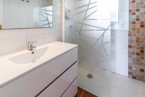 y baño blanco con lavabo y ducha. en Carboneras 48 Apartamento en primera línea de mar, en Girona