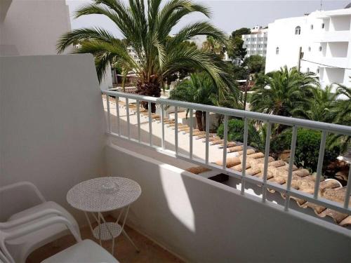a balcony with a table and chairs and palm trees at Hostal Oasis Dor in Cala d´Or