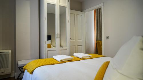 1 dormitorio con 1 cama con 2 toallas en Apartamentos Puente Romano Suites Parking Gratis, en Mérida