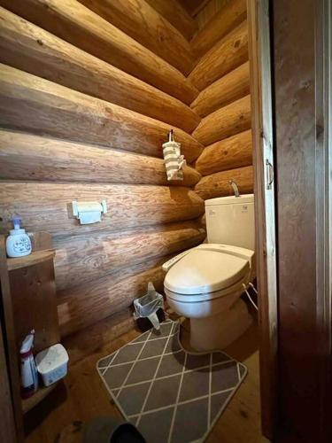 a bathroom with a toilet in a wooden wall at 天空リゾートヴィラのらのら in Mure