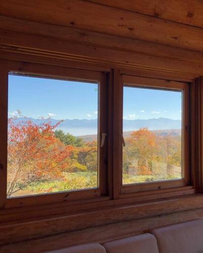 two windows in a room with a view of trees at 天空リゾートヴィラのらのら in Mure
