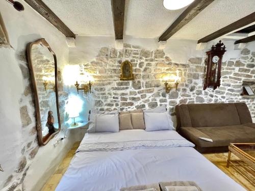 a bedroom with a bed and a stone wall at Old town house with private garden in Budva