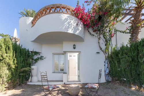 une maison blanche avec une arche, des chaises et des fleurs dans l'établissement MONKÓ VILLA CASABLANCA, à Benalmádena