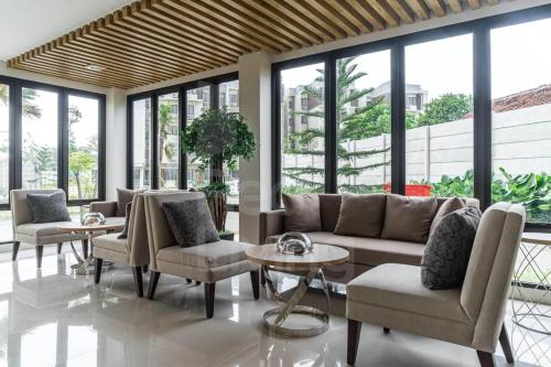 a living room with couches and tables and windows at RedLiving Apartemen Eco Home - Wieg's Room Tower B Yashinoki in Tangerang