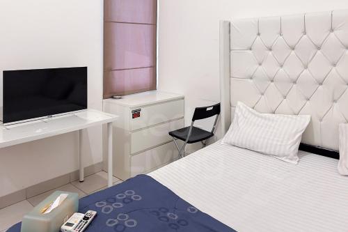 a bedroom with a bed and a tv and a chair at RedLiving Apartemen Eco Home - Wieg's Room Tower B Yashinoki in Tangerang