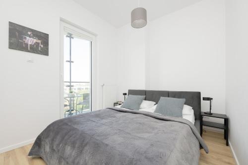a white bedroom with a bed and a window at Cozy Apartments Warsaw Wola Kasprzaka by Renters in Warsaw