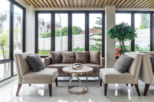 a living room with a couch and two chairs and a table at RedLiving Apartemen Eco Home - Wieg's Room Tower B Yashinoki in Tangerang