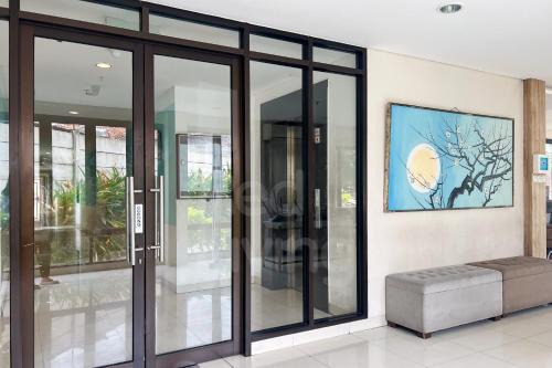a room with glass doors and a bench at RedLiving Apartemen Eco Home - Wieg's Room Tower B Yashinoki in Tangerang