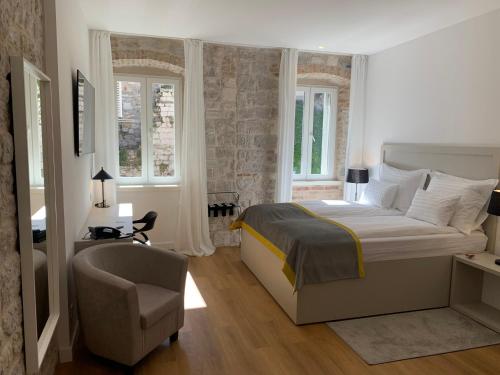 Schlafzimmer mit einem Bett, einem Stuhl und Fenstern in der Unterkunft Priuli Luxury Rooms in Split