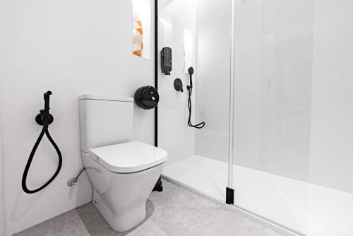 a white bathroom with a shower and a toilet at Hostal Paris in Valladolid