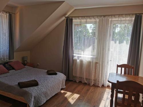 1 dormitorio con cama, mesa y ventanas en Wędzarnia pod lasem - Pokoje, en Mrągowo