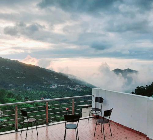 a balcony with chairs and a view of a mountain at Surya Regency premium in Kasauli