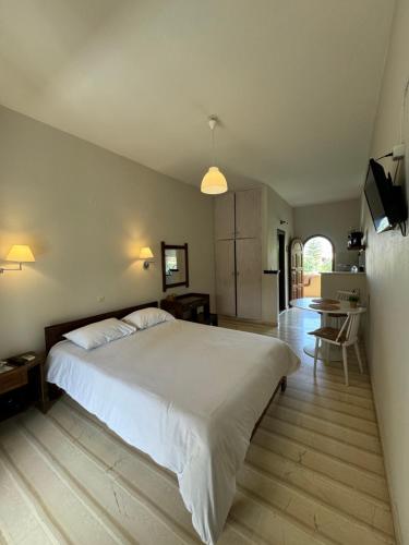 um quarto com uma grande cama branca e uma cozinha em Olive Garden Studios & Apartments em Acharavi