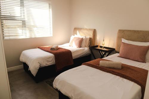 um quarto de hotel com duas camas e uma janela em Modern 2 Bedroom 2 Bathroom Apartment Incl Gym em Ballito