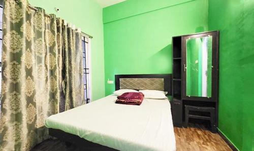 um quarto verde com uma cama e um espelho em FabExpress MK Homes em Kodaikanal