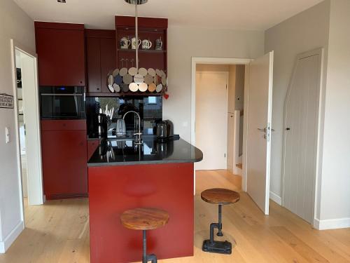una cucina con bancone rosso e sgabelli di Appartement Wattsein a Morsum