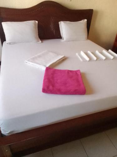 a white bed with a pink pillow on it at Astra 7 in Kigali