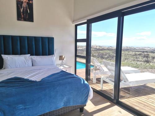 a bedroom with a bed and a balcony with a view at Walkerbay Dunes Lodge in Stanford