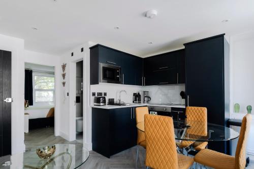a kitchen with black cabinets and a glass table at Comfortable Apartments near Harrods in London