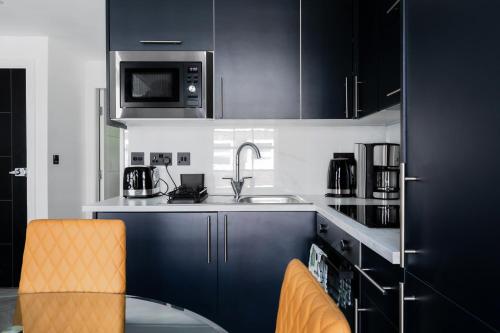 a kitchen with blue cabinets and a sink and a microwave at Comfortable Apartments near Harrods in London