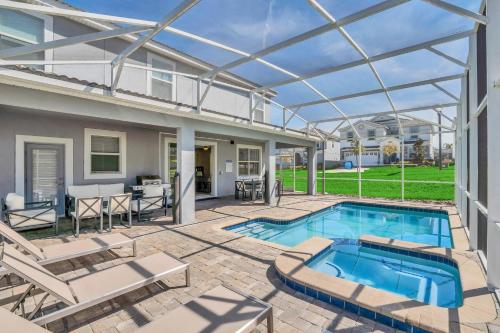 een patio met een zwembad en een huis bij 8BR Luxury - Sleeps 22 - Near Disney with Pool & Hot Tub! in Davenport