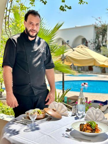 a man standing in front of a table with food at Palm Djerba Suites in Mezraya