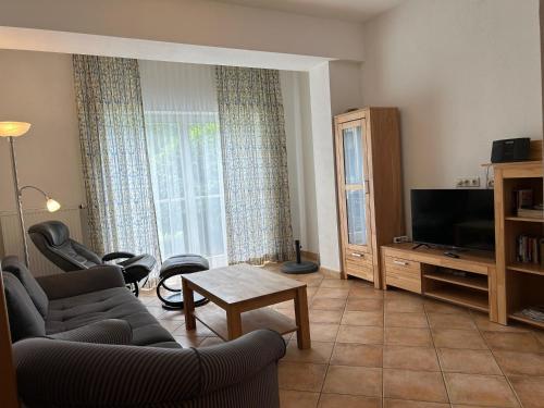 uma sala de estar com um sofá e uma televisão em Gabi mit Pool und Sauna em Übersee