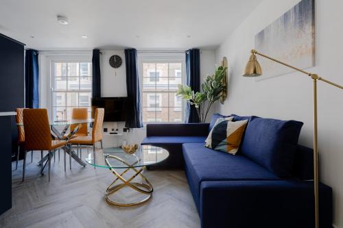 a living room with a blue couch and a table at Comfortable Apartments near Harrods in London