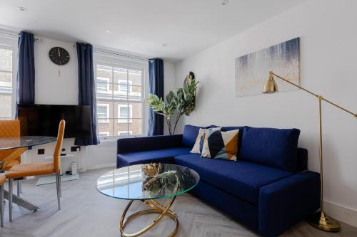 a living room with a blue couch and a glass table at Comfortable Apartments near Harrods in London