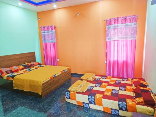 2 Betten in einem Zimmer mit rosa und orangefarbenen Wänden in der Unterkunft Sahara premium family homestay in Mysore