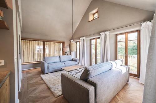 a living room with a couch and chairs and windows at Das Flachshaus Boutique Apartments in Aidling
