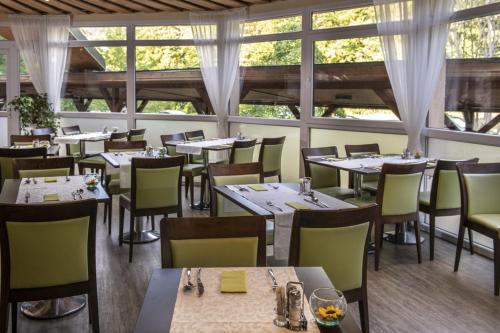 a restaurant with tables and chairs and windows at Patak Park Hotel Visegrád in Visegrád