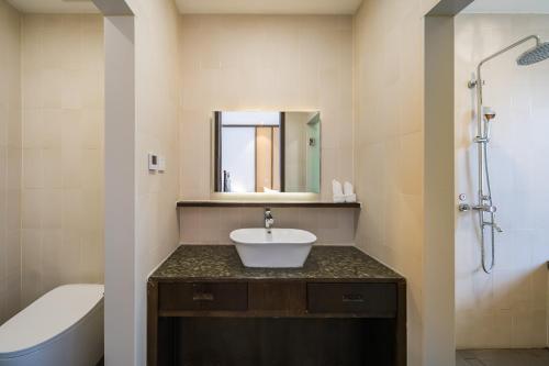a bathroom with a sink and a toilet and a tub at Dasein Youlan Hotel in Beijing