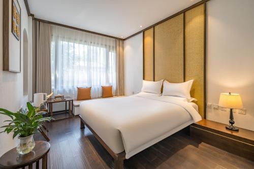 a bedroom with a large white bed and a window at Dasein Youlan Hotel in Beijing