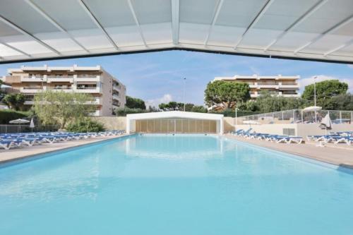 une grande piscine avec des chaises et un bâtiment dans l'établissement 06U - Beautiful studio in residence - swimming pool and tennis court, à Saint-Laurent-du-Var
