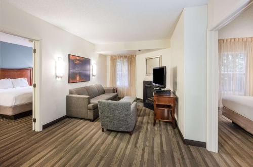 a hotel room with a bed and a living room at Hyatt House Herndon/Reston in Herndon