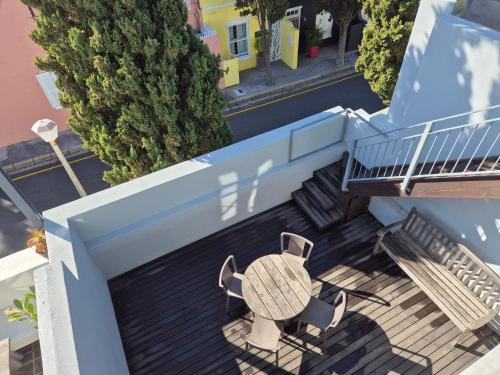 una mesa y sillas en un balcón con escaleras en De Waterkant Cottages, en Ciudad del Cabo