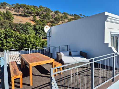 einen Balkon mit einem Holztisch und einem Sofa in der Unterkunft De Waterkant Cottages in Kapstadt