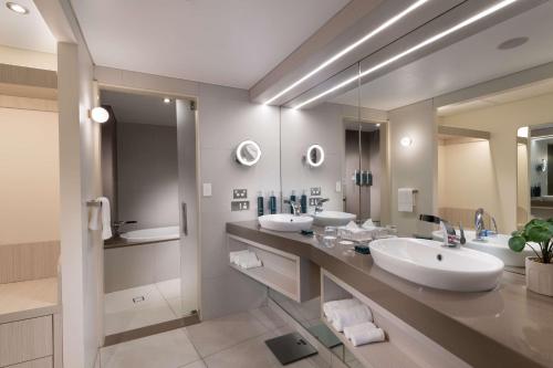baño con 2 lavabos y espejo grande en Hilton Darwin, en Darwin