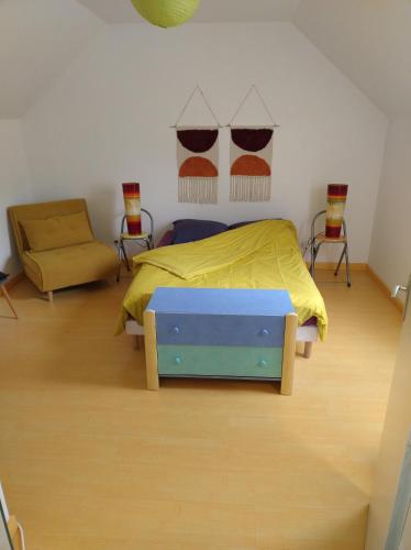 a bedroom with a bed with a yellow blanket and a chair at Escale Élégante à Héricourt in Héricourt