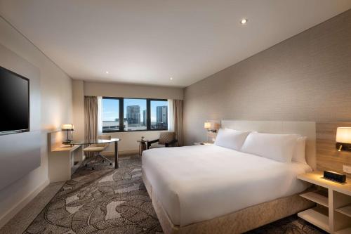 una habitación de hotel con una gran cama blanca y una ventana en Hilton Darwin en Darwin