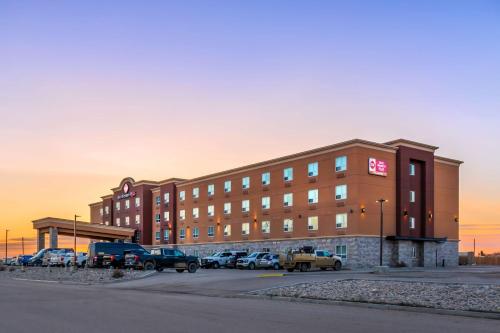 a large building with cars parked in a parking lot at Best Western Plus Kindersley Hotel in Kindersley