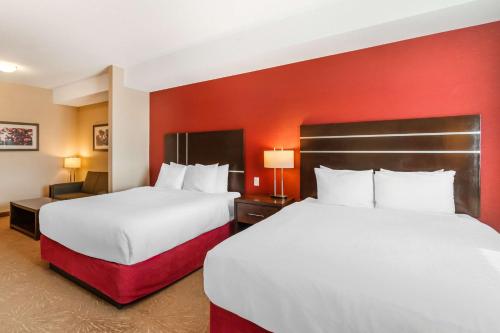 two beds in a hotel room with red walls at Best Western Plus Kindersley Hotel in Kindersley
