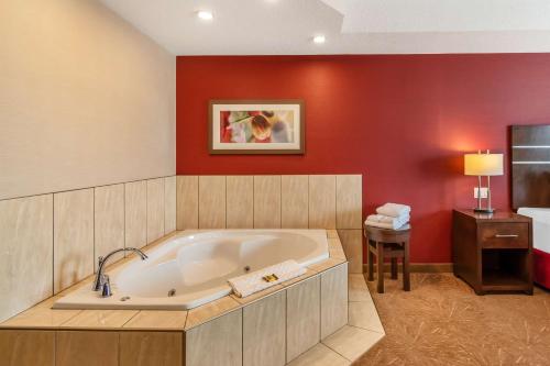 a large bath tub in a room with a red wall at Best Western Plus Kindersley Hotel in Kindersley
