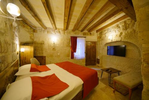 a bedroom with a bed and a tv in a room at Vezir Cave Suites in Goreme