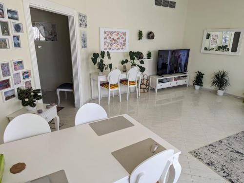 a living room with white tables and chairs and a tv at Home stay - FEMALE GUEST ONLY -ممنوع دخول الرجال in Sharjah
